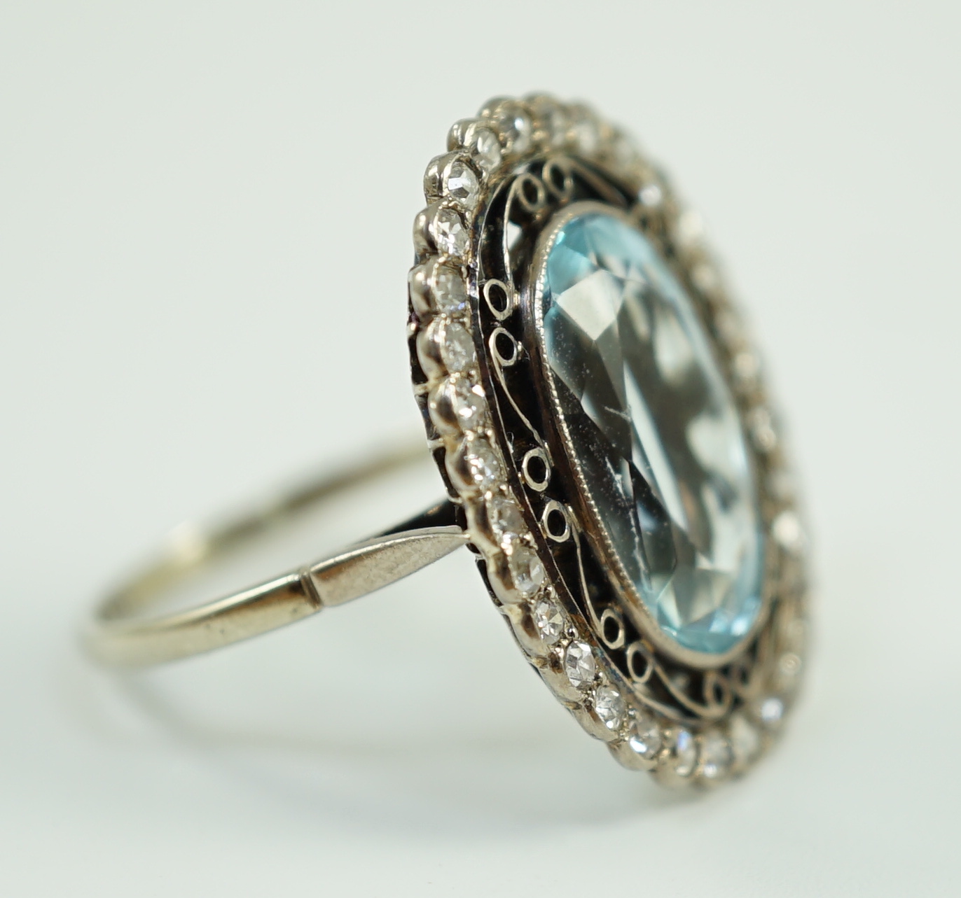 An 18ct white gold and single stone oval cut aquamarine set dress ring, with brilliant cut diamond set border